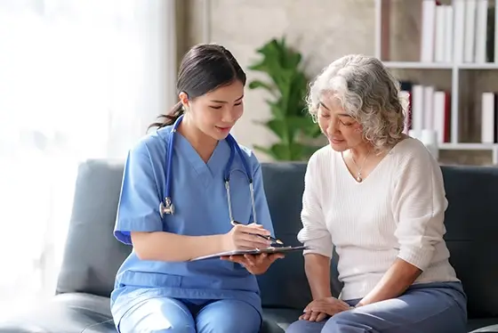 Nurse Discussing Health Care Options with an Elderly Woman on Sofa
